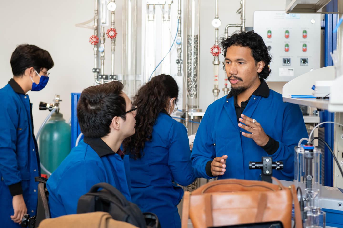 Students and professor inside a lab wearing blue coats